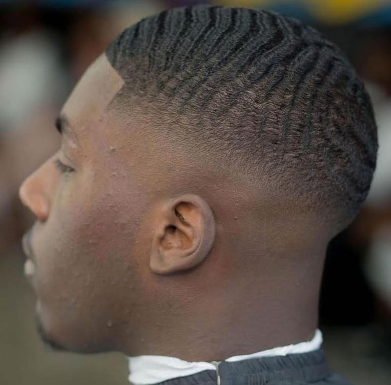 Side profile of a man with a short fade haircut featuring textured wave pattern on top