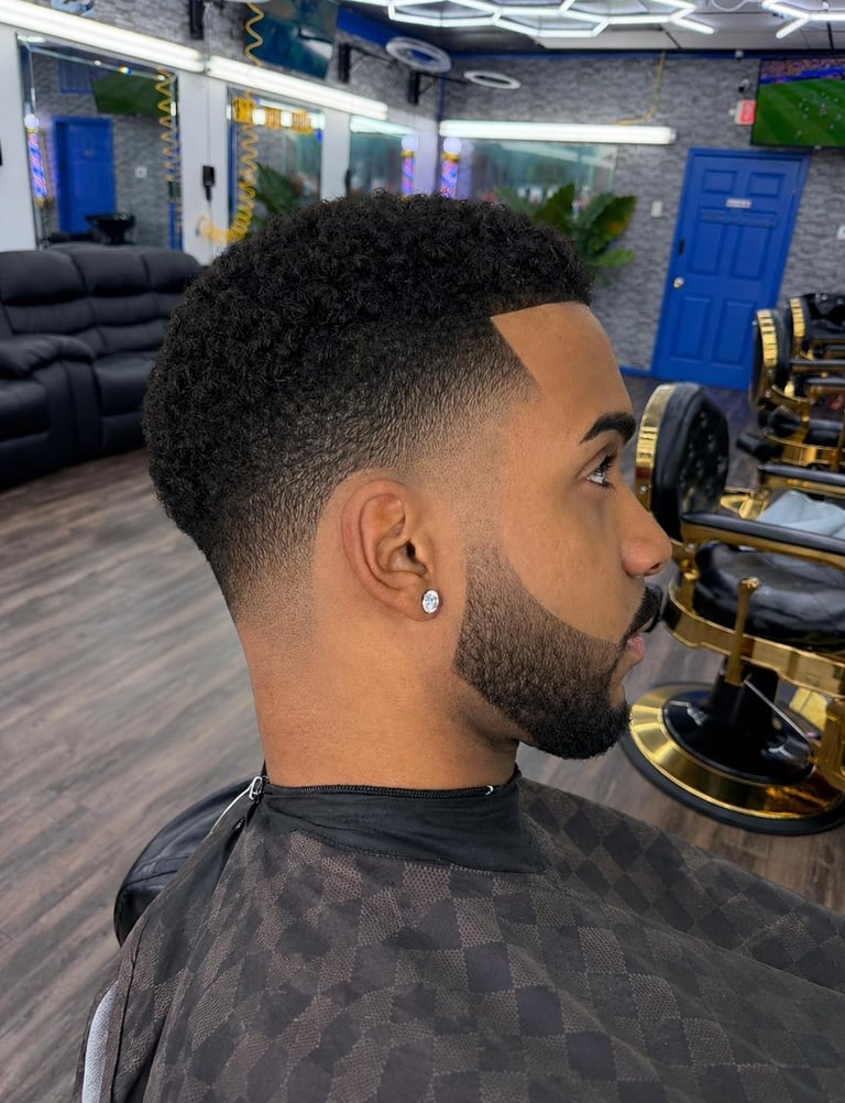 Man with short textured hair and full beard shown in profile inside a modern barber shop with blue accents and gym equipment